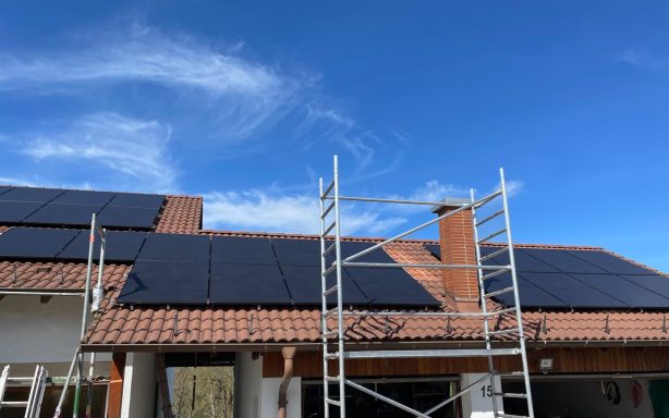 Auf dem Dach eines Hauses sind Solarpaneele installiert, ein Gerüst ist sichtbar.